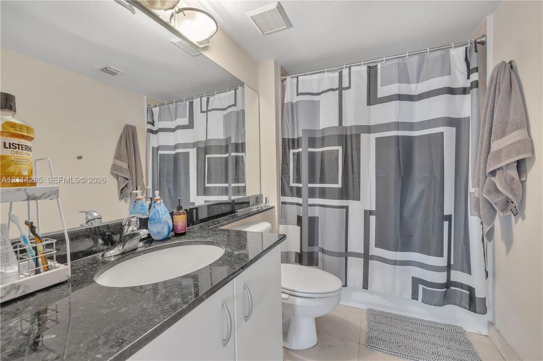 Bathroom featuring a vanity with a stone countertop, an integrated oval sink, a full-width wall mirror, and a porcelain commode