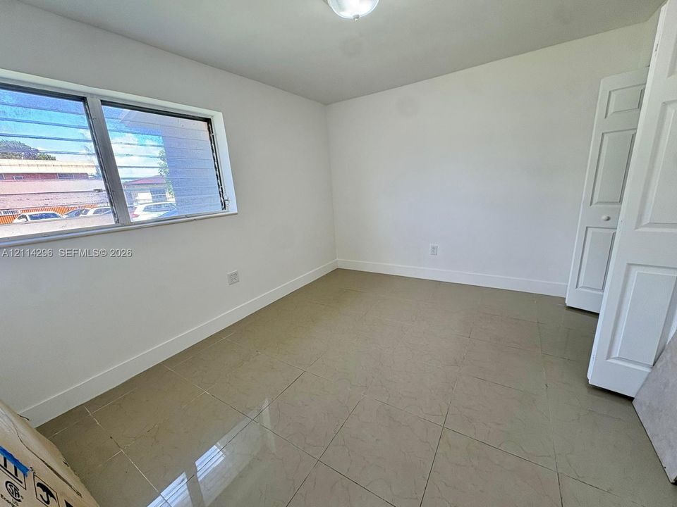 Interior space featuring large-format ceramic tile flooring, neutral wall paint, a multi-pane slider window, and paneled closet doors