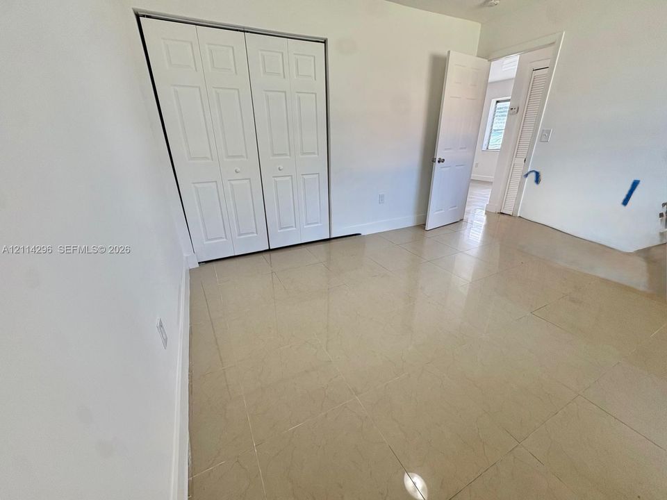Neutral-toned large-format tile flooring, white bi-fold closet doors, and traditional six-panel interior doors