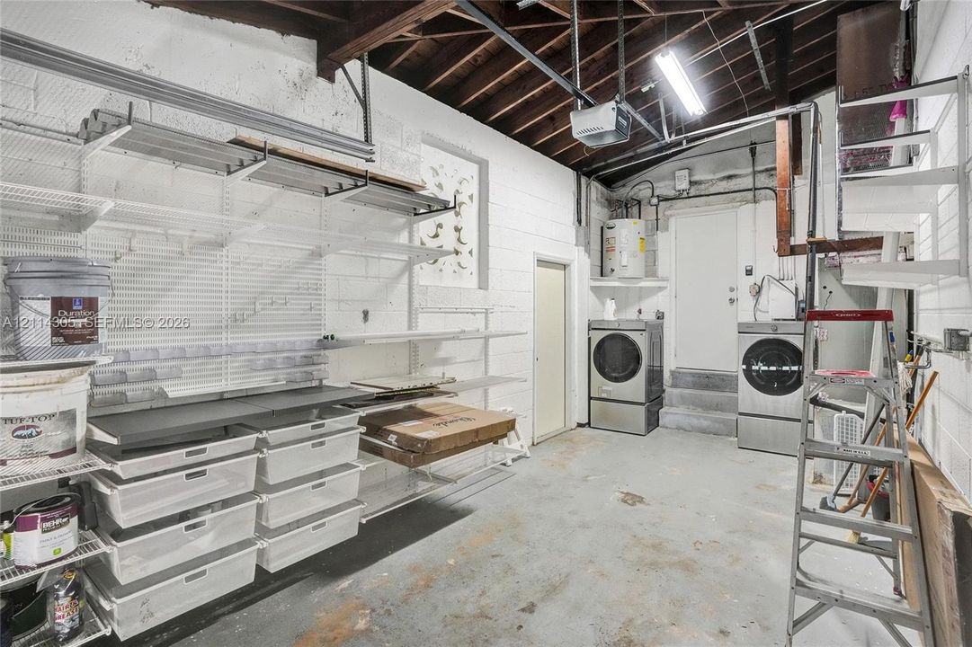Utility area featuring built-in wire shelving, integrated storage bins, exposed ceiling beams, and concrete flooring