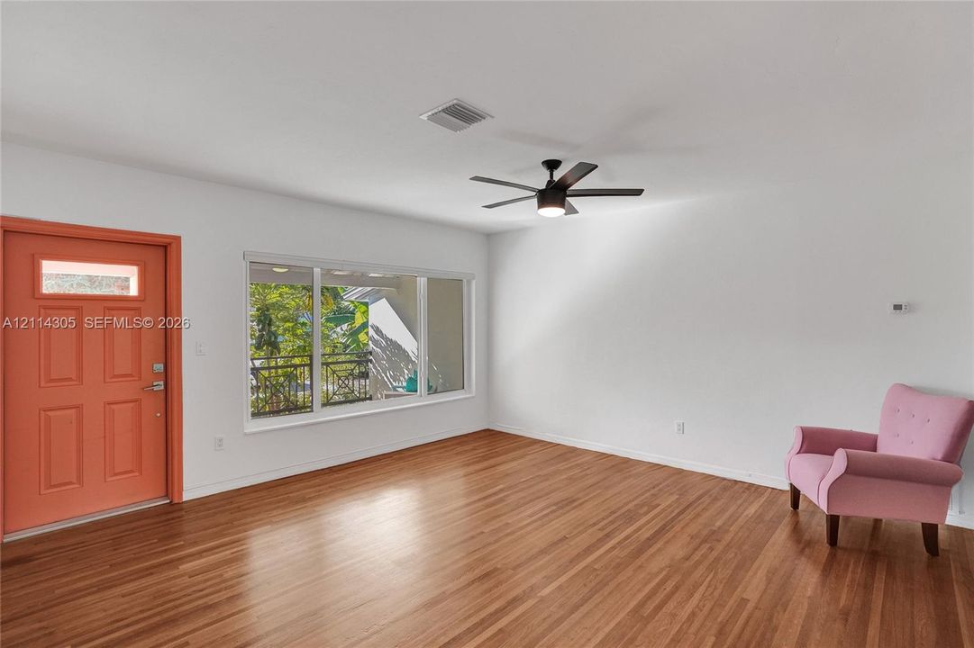 Interior space featuring wood-finish flooring, a large picture window, a ceiling-mounted light fixture with fan, and a paneled exterior door