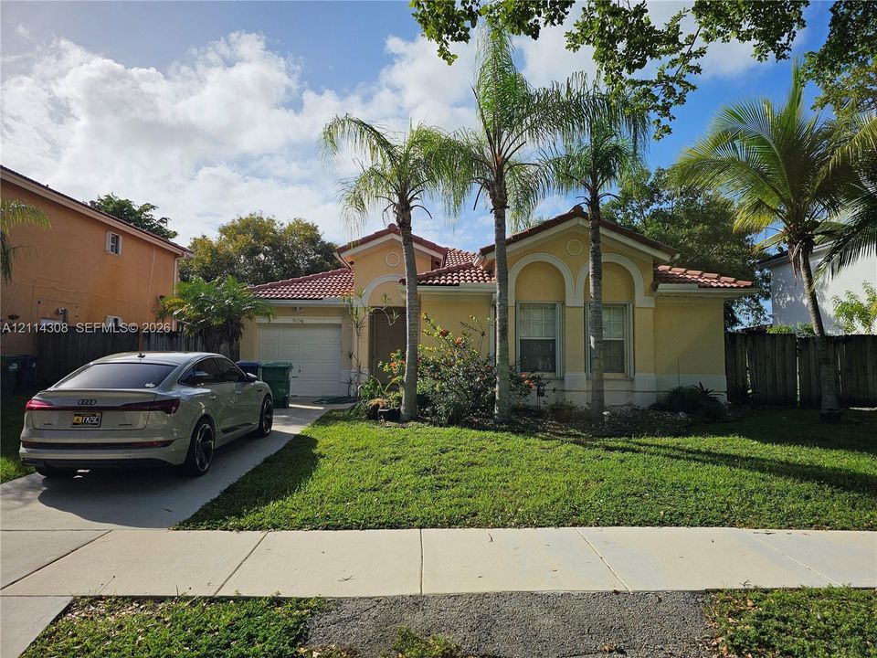 Single-story residence featuring a tile roof, stucco exterior, arched window detailing, and an attached garage