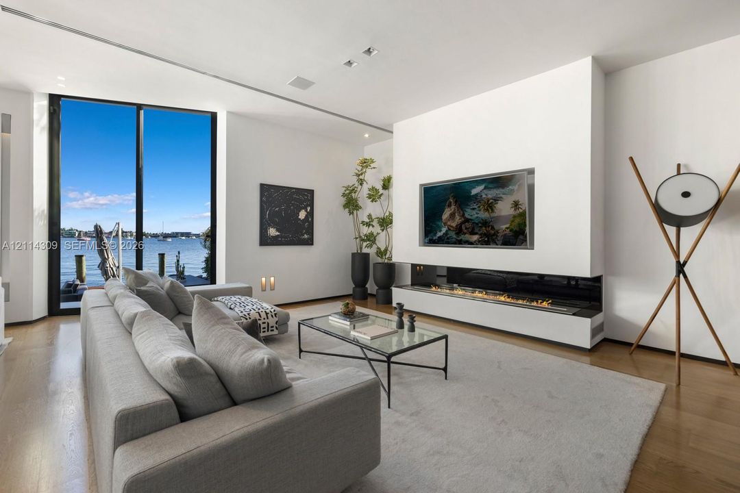 Floor-to-ceiling glass wall, linear built-in fireplace, wood-finish flooring, and recessed ceiling lighting