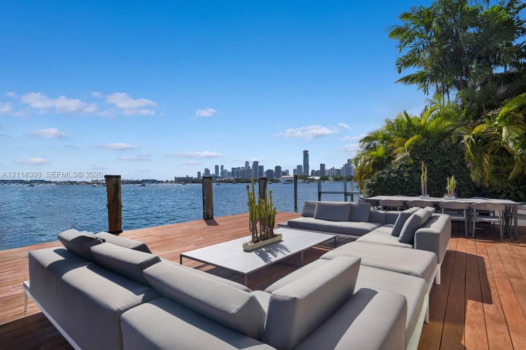Waterfront deck featuring wood-finish decking, pilings, and mature palm trees