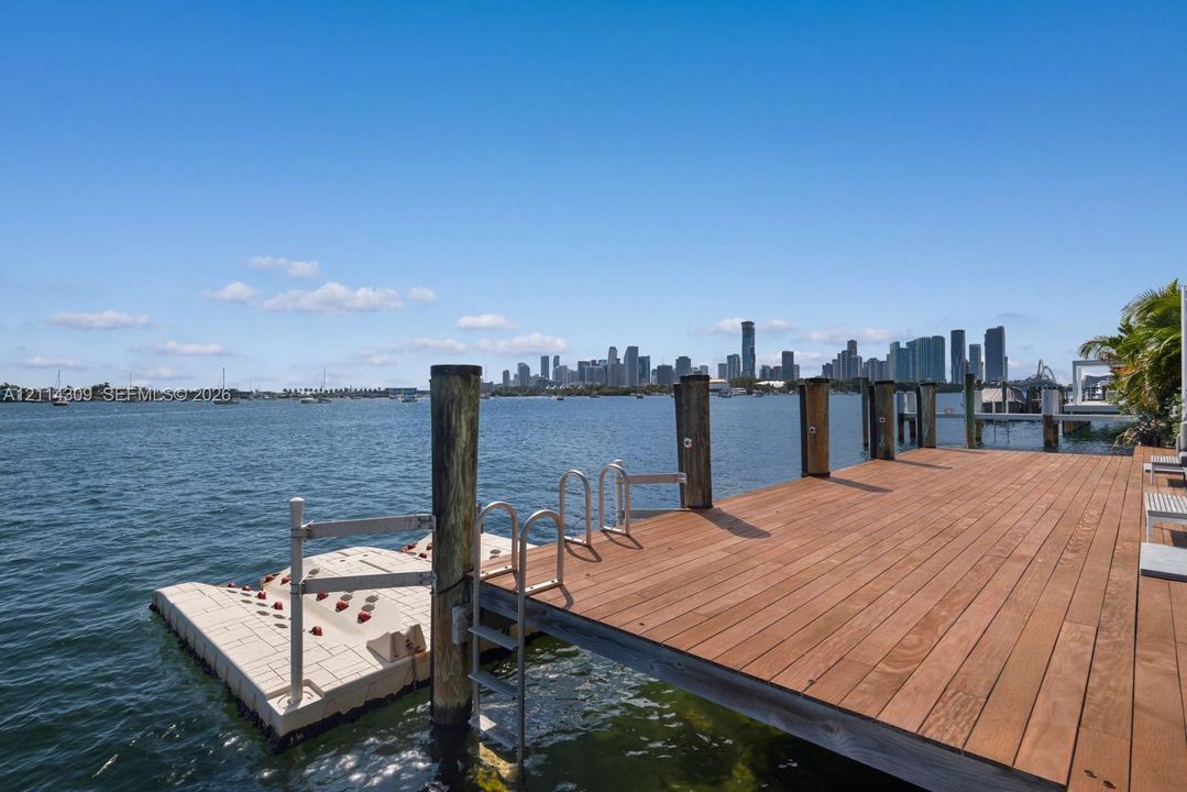 Private wooden dock featuring a floating platform, stainless steel ladders, and bulkhead pilings overlooking the waterfront and city skyline