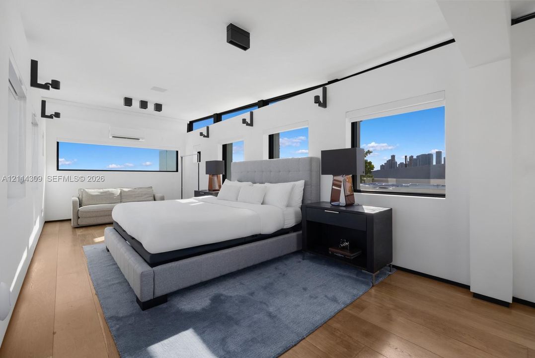 Wood-finish flooring, clerestory windows, black-finished wall-mounted lighting, and rectangular windows featuring exterior city scenery
