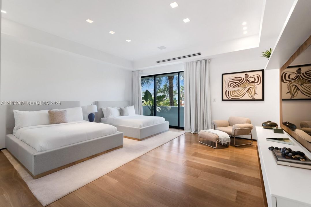 Wood-finish flooring, recessed ceiling lighting, tray ceiling detail, and floor-to-ceiling sliding glass doors opening to a balcony