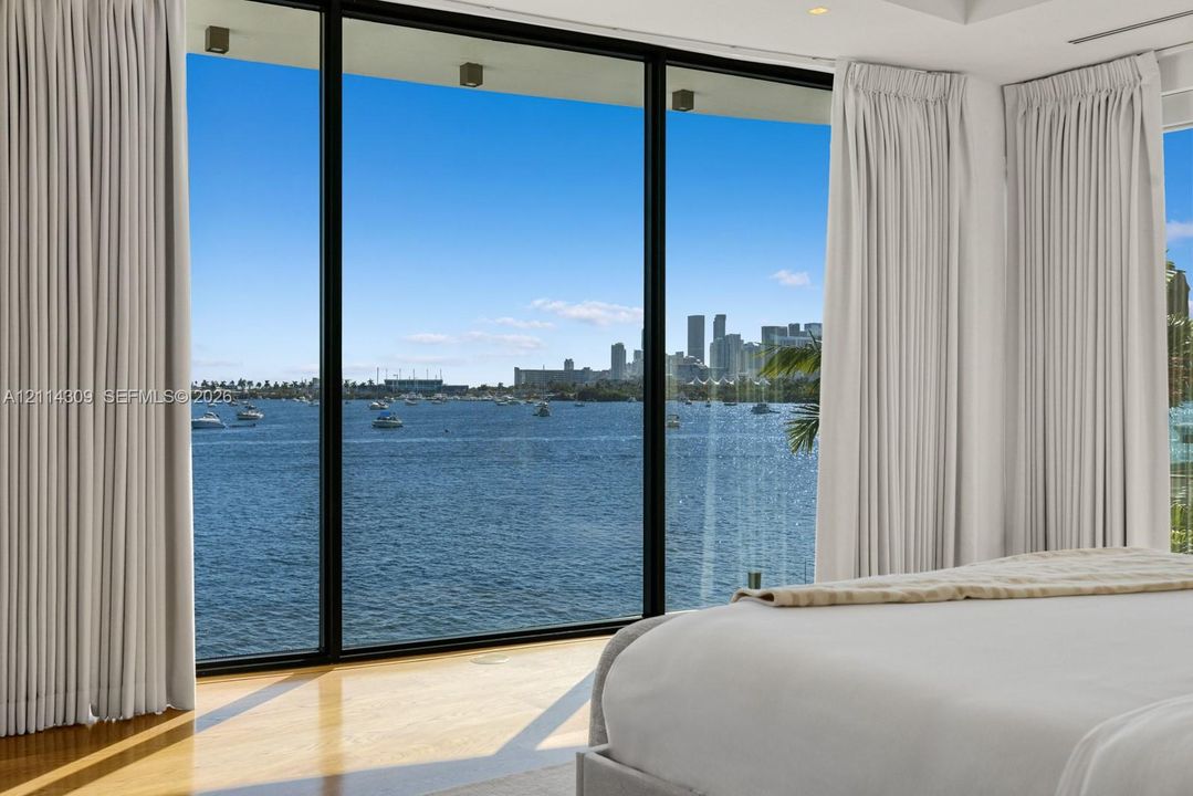 Floor-to-ceiling windows with black metal frames, water-front exposure, hardwood flooring, and recessed ceiling lighting