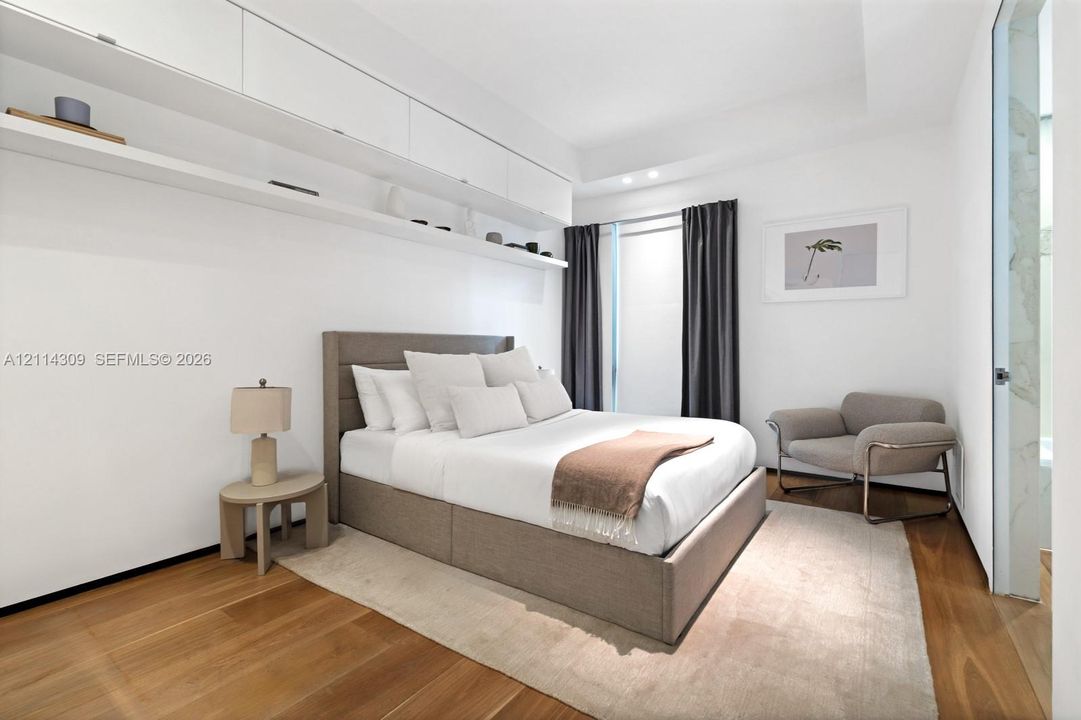 Wood-finish flooring, white built-in wall cabinetry with integrated shelving, and recessed ceiling lighting