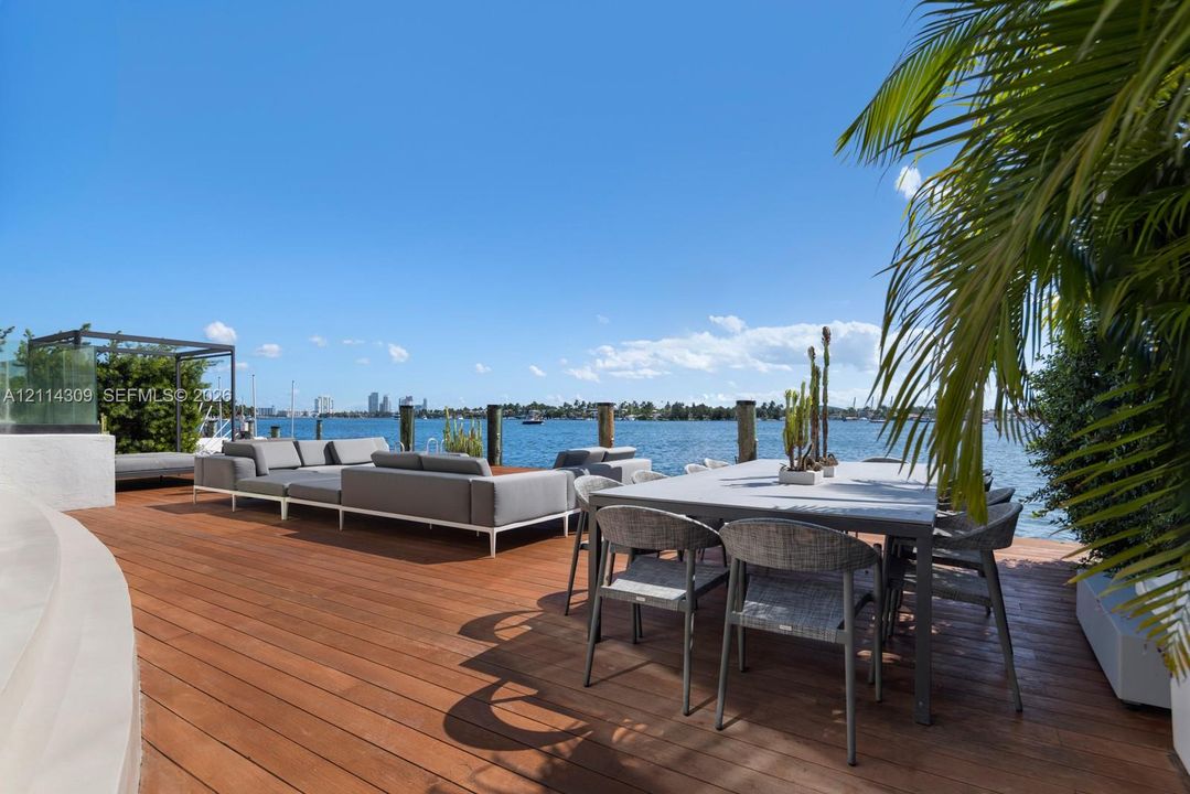 Waterfront deck featuring wood-finish flooring, glass railing, and wood pilings