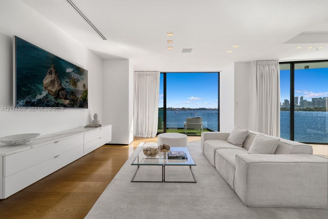 Living area featuring floor-to-ceiling glass, wood-finish flooring, recessed lighting, and built-in white cabinetry