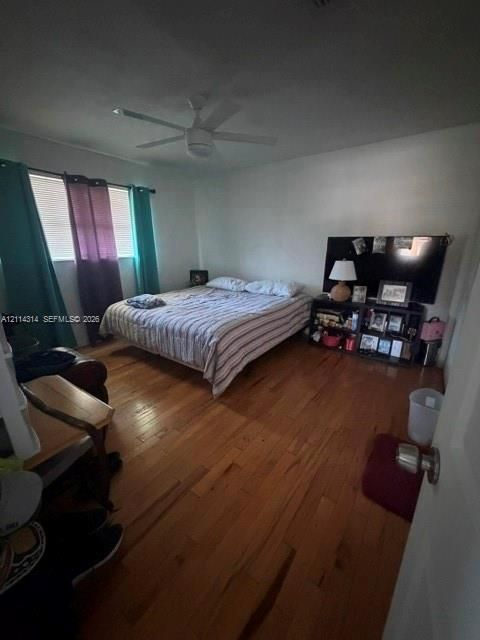 Room featuring wood-finish flooring, a multi-blade ceiling fan, and horizontal blinds