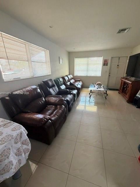 Large-format neutral tile flooring throughout with recessed lighting and multiple windows featuring horizontal blinds