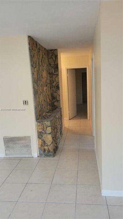 Interior hallway featuring tile flooring and a built-in floor-to-ceiling stone accent wall