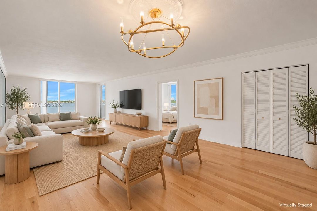 Living area featuring light-toned wood-finish flooring, a modern gold-tone circular chandelier, crown molding, and floor-to-ceiling windows