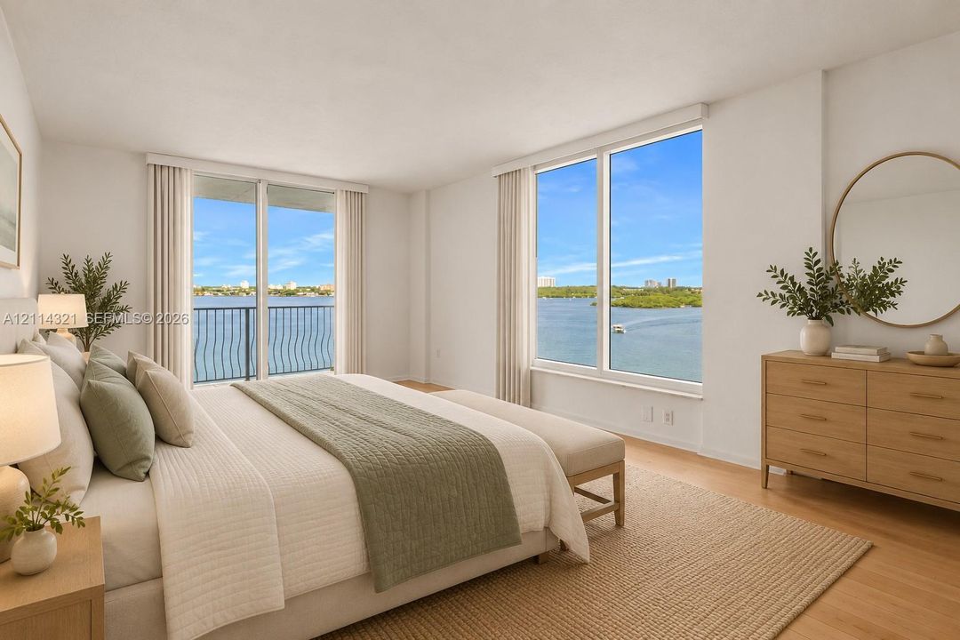Spacious bedroom featuring light wood-finish flooring, floor-to-ceiling windows with water scenery, and a private balcony with metal railing