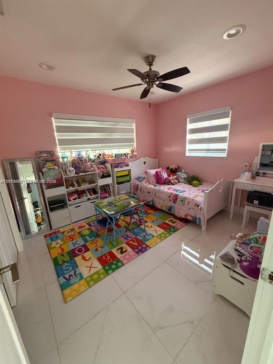 Interior room featuring large-format polished tile flooring, recessed ceiling lighting, a multi-blade ceiling fan, and windows equipped with horizontal roller shades
