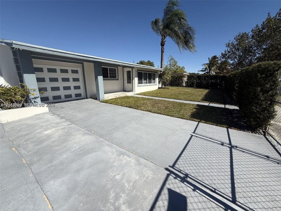 Single-story exterior featuring a painted stucco facade, attached one-car garage, concrete driveway, and a front lawn with established landscaping