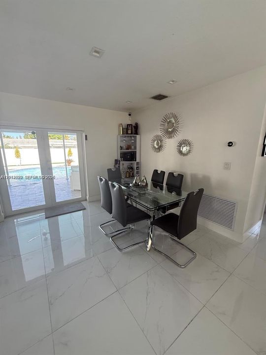 Large-format white tile flooring, built-in corner display shelving, recessed lighting, and glass-paneled double doors providing outdoor access