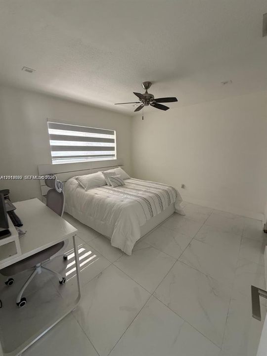 Neutral-toned room featuring large-format tile flooring, recessed lighting, and a multi-speed ceiling fan