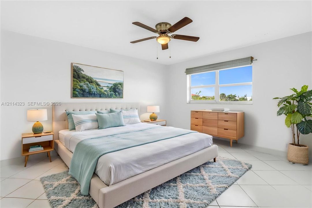 VIRTUALLY STAGED. Bright room featuring neutral wall finishes, tile flooring, a multi-blade ceiling fan with integrated light fixture, and large windows with horizontal blinds