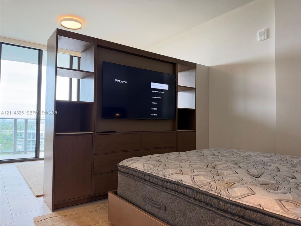 Built-in floor-to-ceiling wood-finish storage unit featuring open shelving, integrated cabinetry, and television mounting