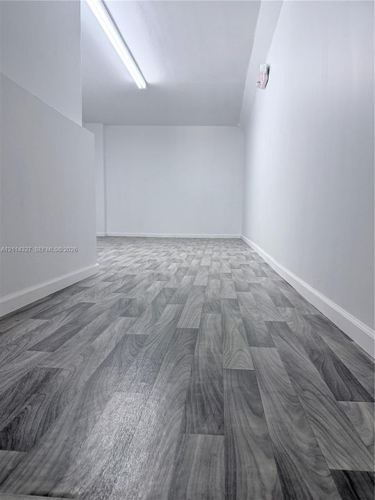 Neutral interior space featuring wood-finish flooring and linear ceiling lighting