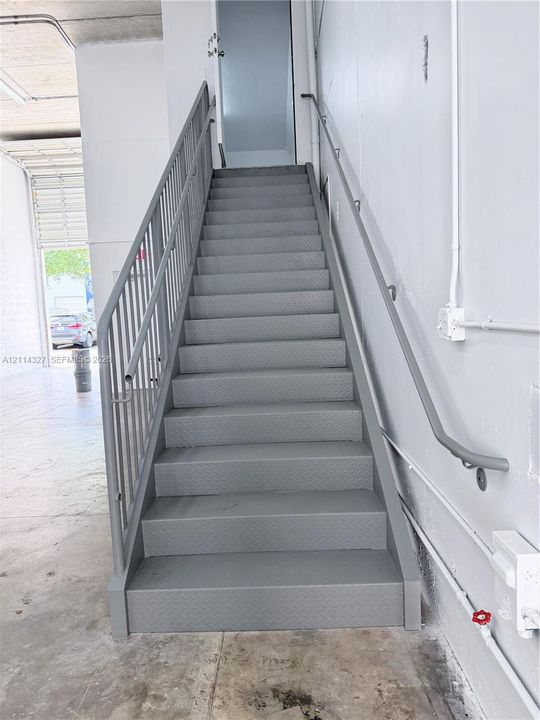 Industrial-style staircase featuring metal tread construction, integrated railing, and wall-mounted handrail