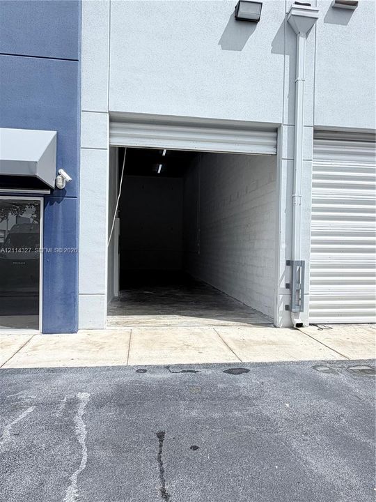 Commercial exterior featuring a roll-up bay door, painted masonry walls, and exterior-mounted lighting fixture