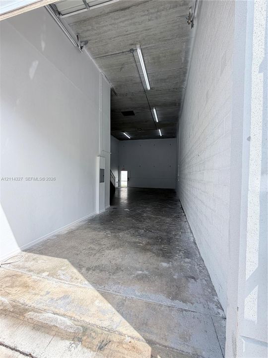 Expansive industrial-style interior featuring high ceilings, exposed concrete finish, durable concrete flooring, and linear LED lighting