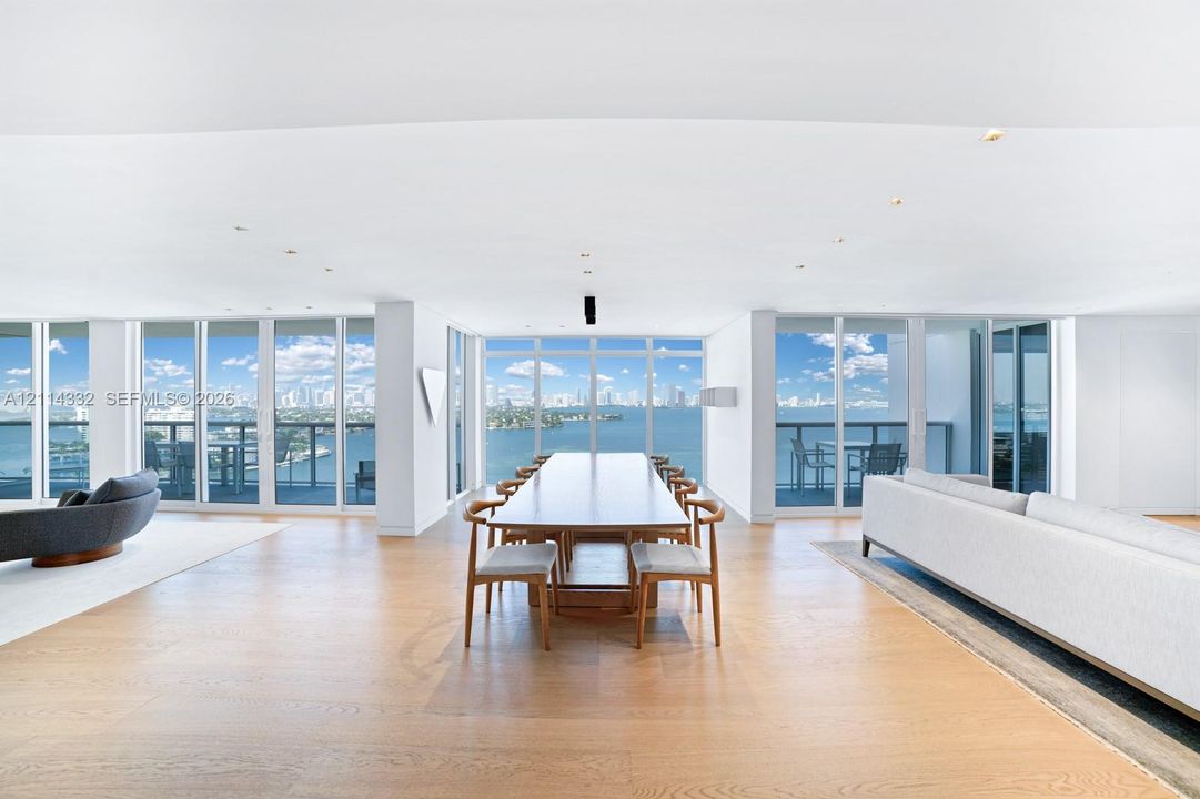 Open-concept living space featuring wood-finish flooring, recessed lighting, and floor-to-ceiling windows with expansive water and city skyline outlooks