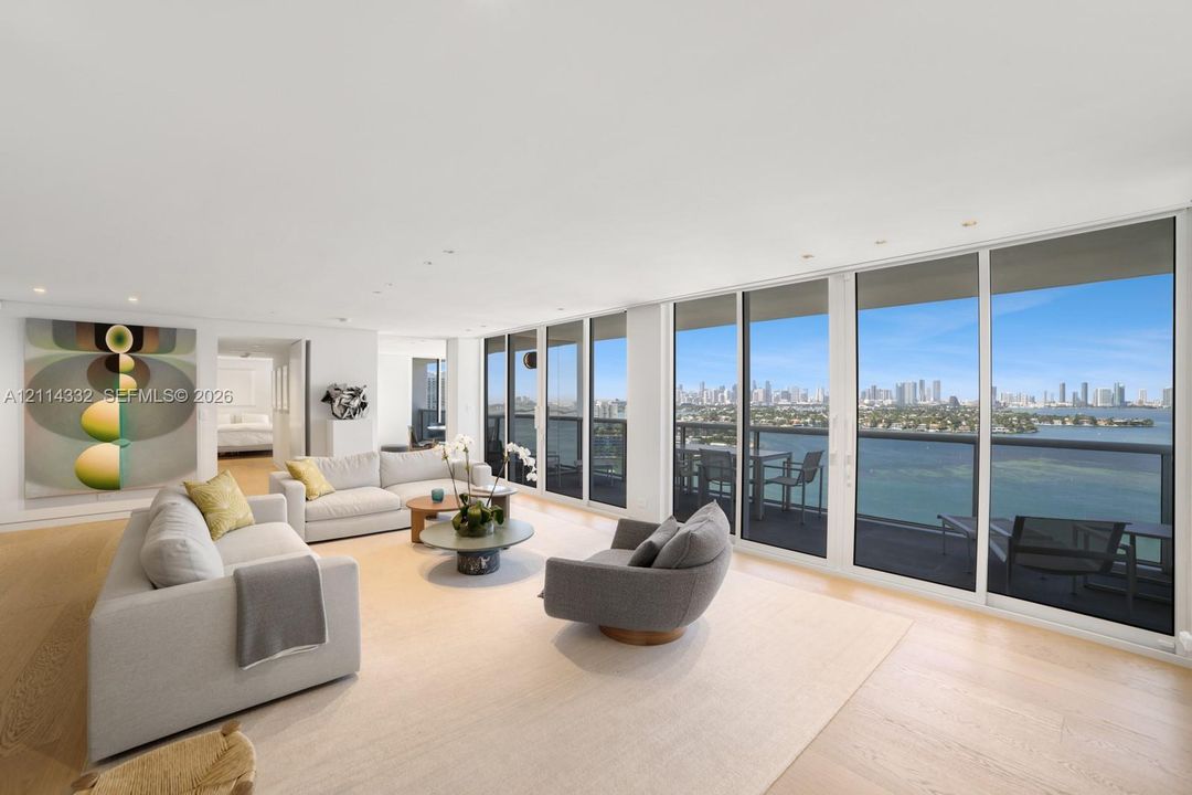 Open-concept living area featuring floor-to-ceiling glass sliding doors, recessed lighting, wood-finish flooring, and a private balcony