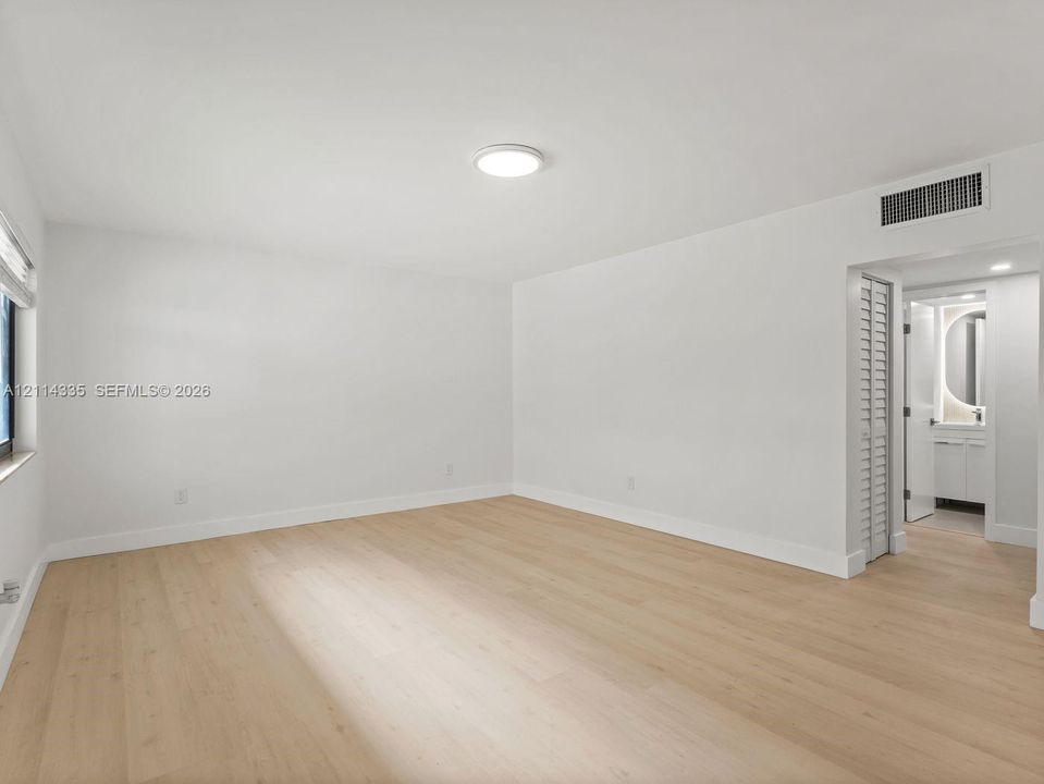 Room featuring wood-finish flooring, a neutral color palette, recessed lighting, and a louvered closet door