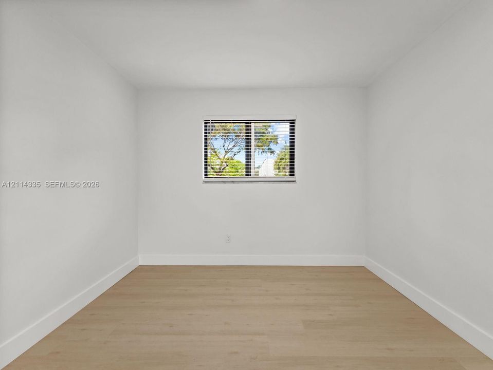 Neutral wall palette, wood-finish flooring, and single-pane window with horizontal blinds