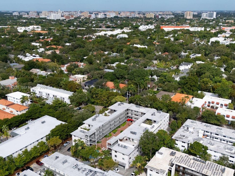 Aerial perspective of a multi-story residential complex featuring a central courtyard with paved hardscaping, perimeter landscaping, and rooftop mechanical systems
