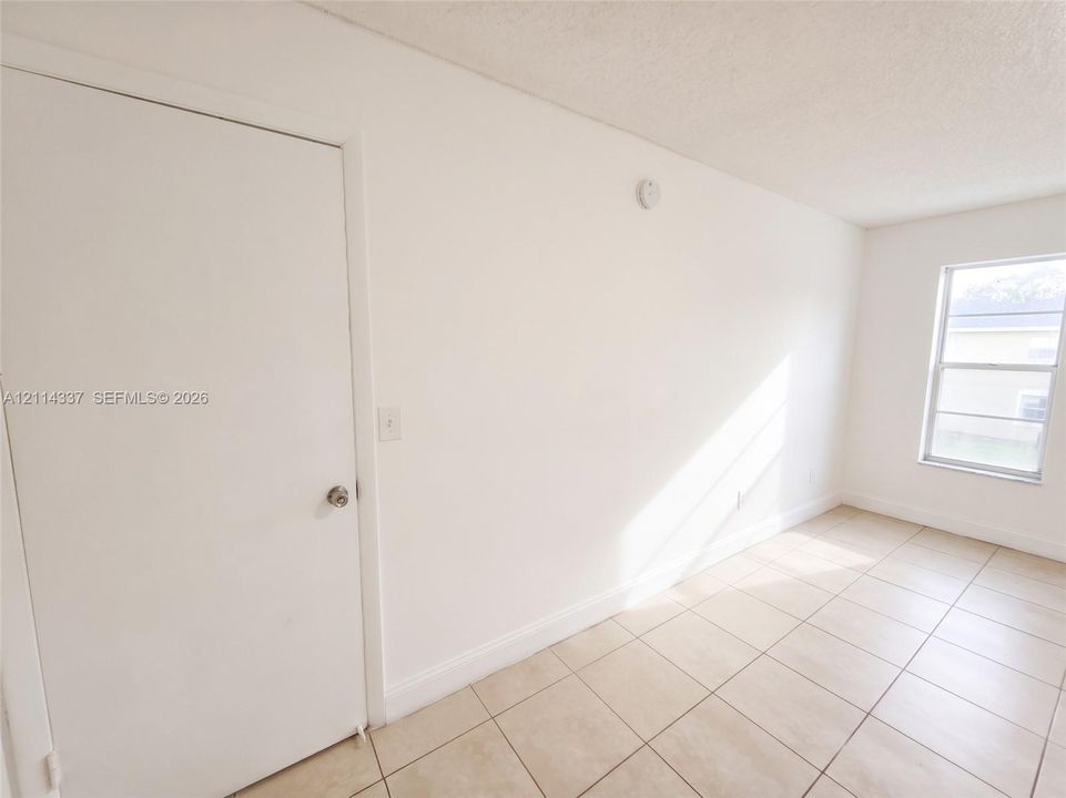 Neutral interior space featuring ceramic tile flooring, a single-panel interior door, and a single-pane window
