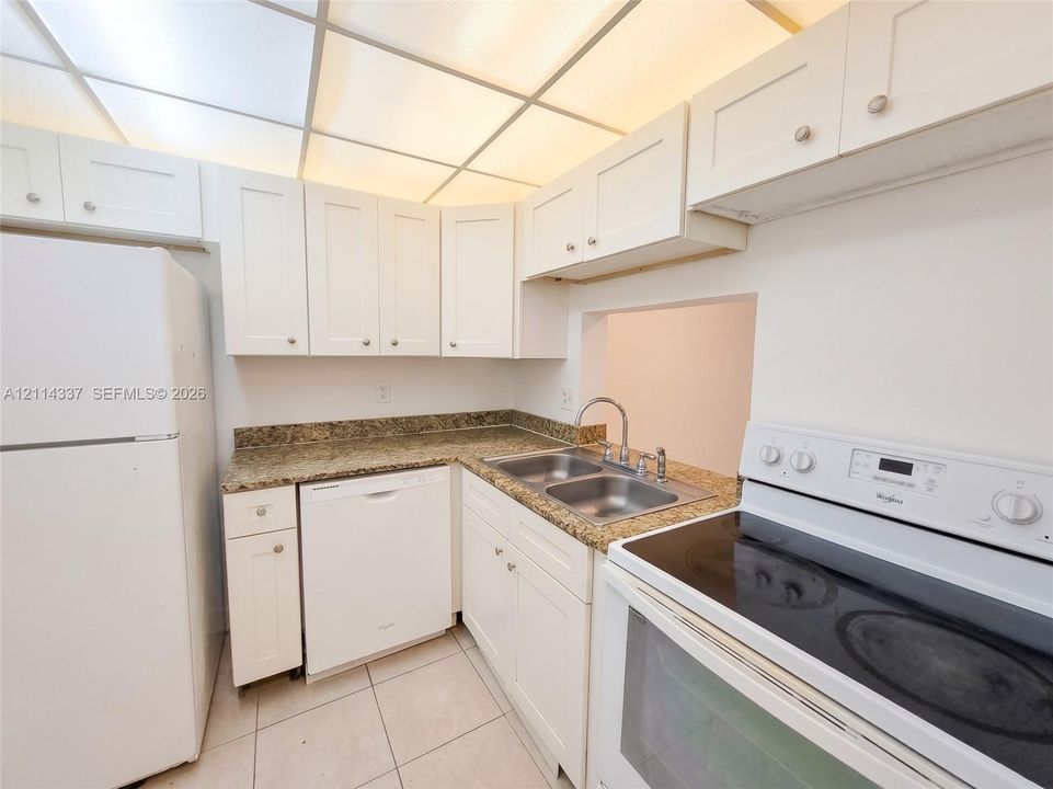 Kitchen featuring white cabinetry, stone countertops, dual-basin stainless steel sink, drop-in electric range, and tile flooring