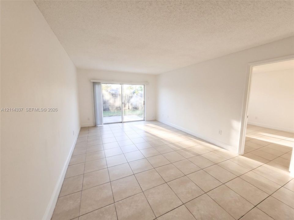 Neutral-toned ceramic tile flooring, sliding glass patio door, and textured ceiling finish