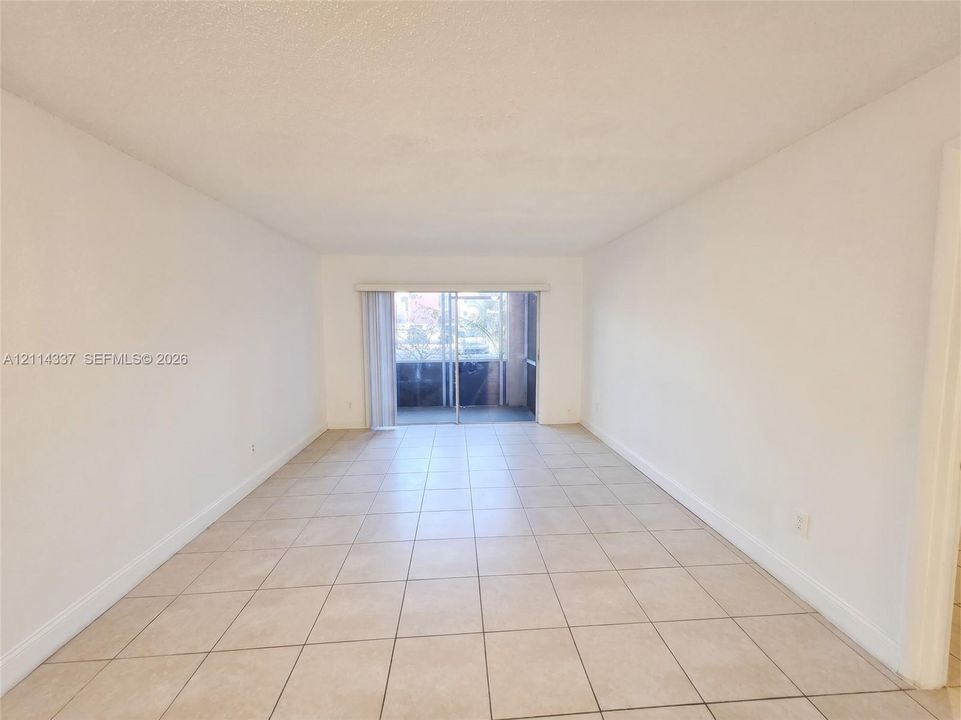 Neutral-toned ceramic tile flooring, clean white wall finishes, and a sliding glass door providing access to a screened-in balcony
