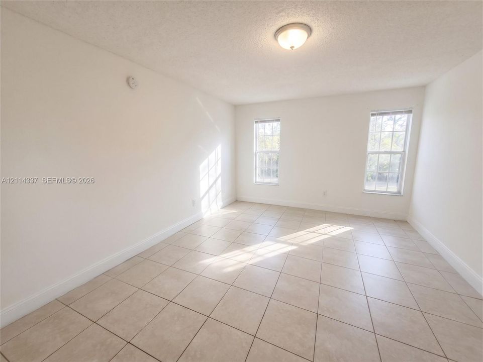 Neutral-toned interior space featuring ceramic tile flooring, two double-hung windows, and a central dome-style ceiling light fixture