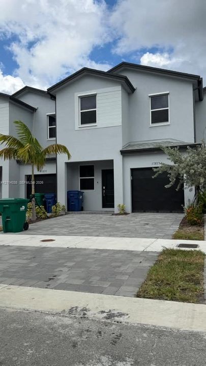 Two-story stucco exterior featuring horizontal siding accents, a paved driveway, and an integrated garage