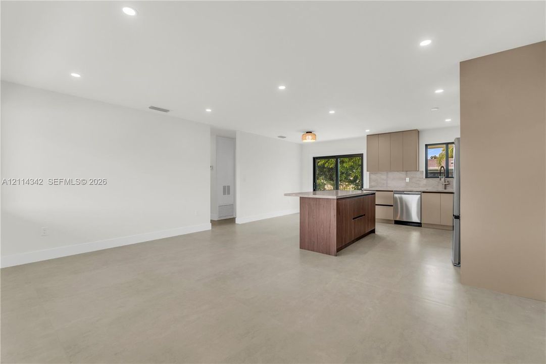 Open-concept kitchen featuring a center island, recessed lighting, stainless steel appliances, flat-panel cabinetry, and large-format tile flooring