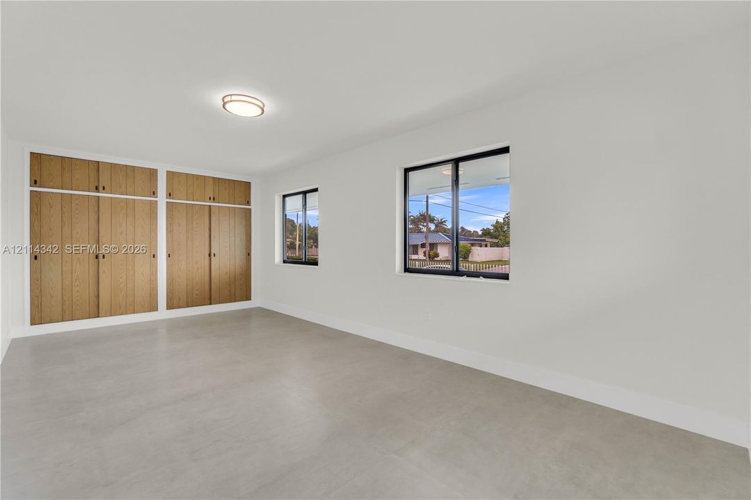 Neutral wall tones, wood-finish built-in cabinetry, large-format tile flooring, and windows with black frames