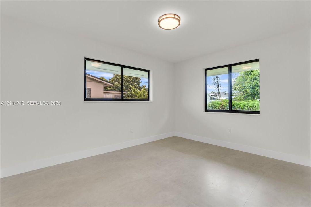 Neutral-toned tile flooring, dual windows with black frames, and a contemporary flush-mount ceiling light fixture