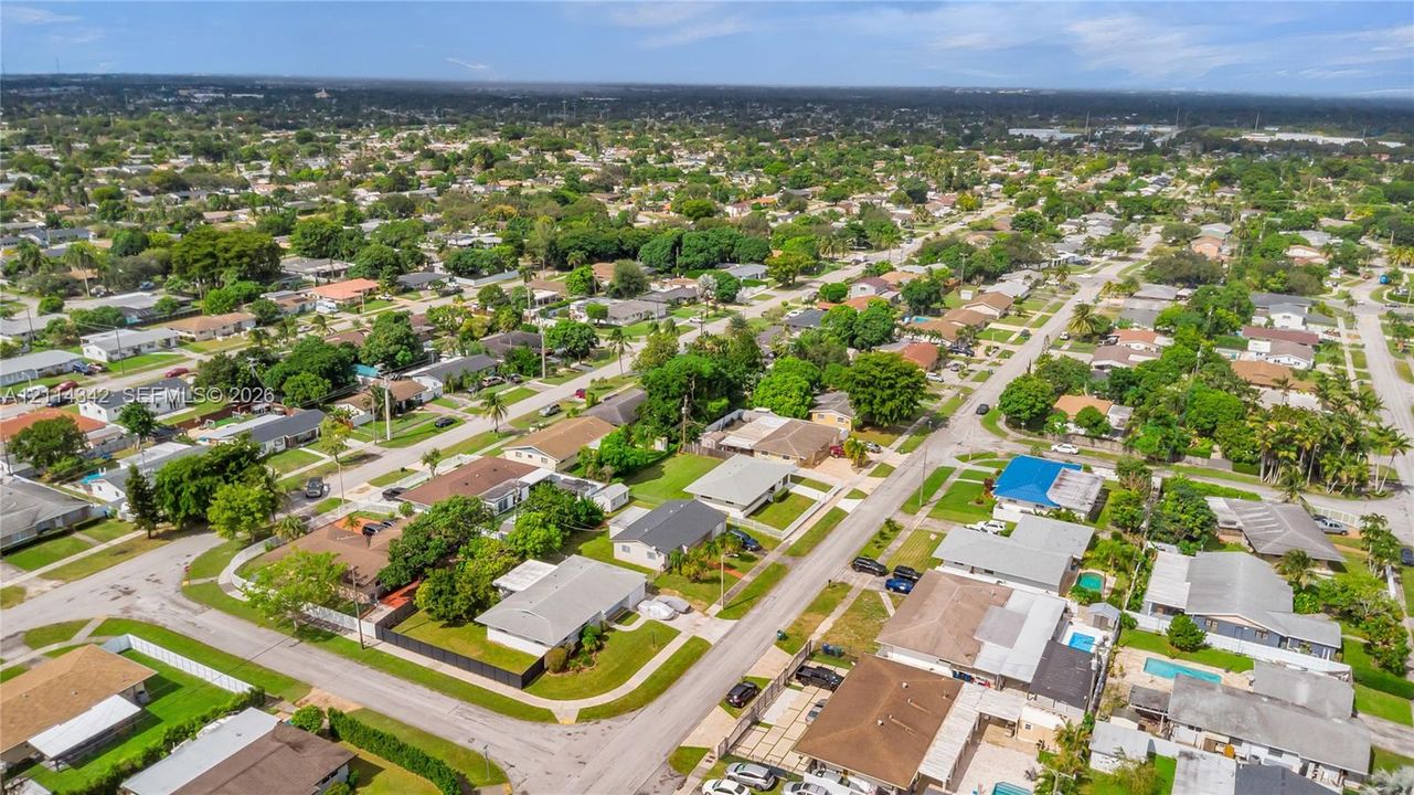 Aerial perspective of a suburban neighborhood featuring tree-lined streets, varied residential rooflines, and established landscaping