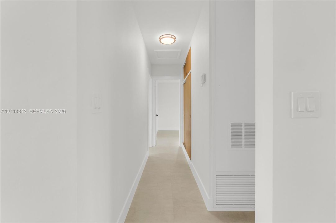 Neutral color palette, tile flooring, flush-mount circular lighting fixture, and floor-to-ceiling wooden cabinetry