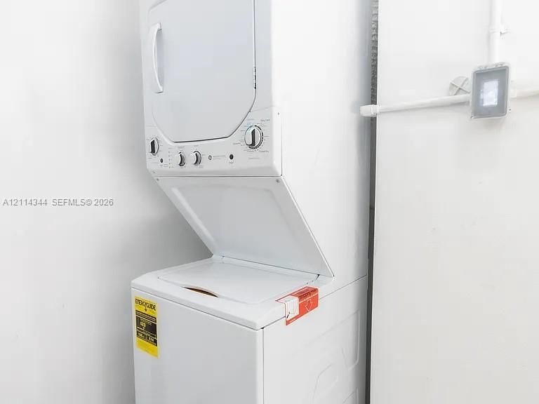 Stacked white laundry unit with top-loading washer and integrated control console