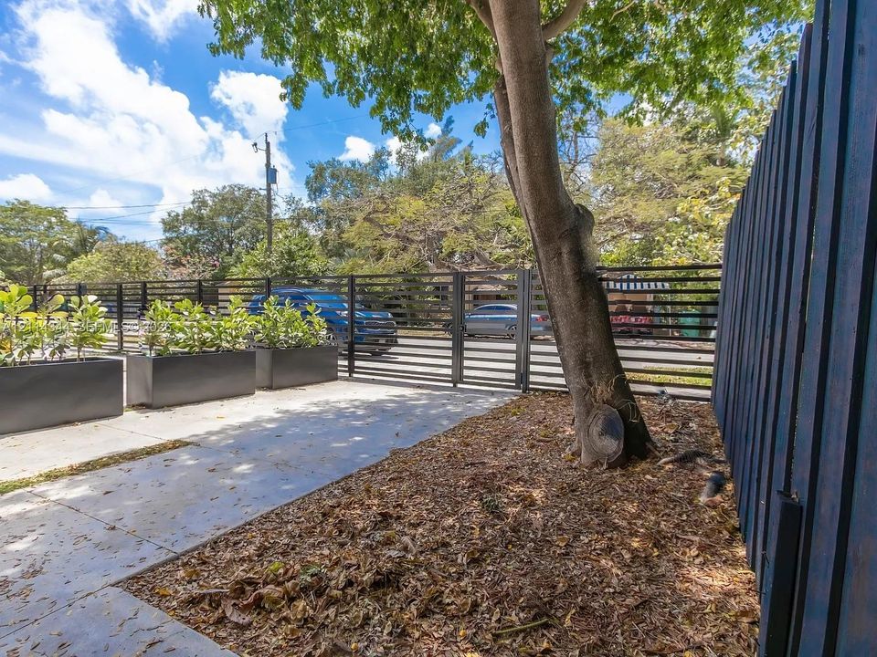 Modern horizontal slat fencing with integrated gate, concrete hardscaping, and large geometric metal planters