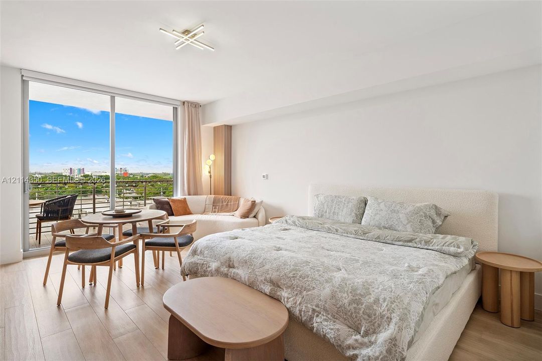 Floor-to-ceiling glass sliding doors, wood-finish flooring, metal balcony railing, modern multi-arm ceiling lighting
