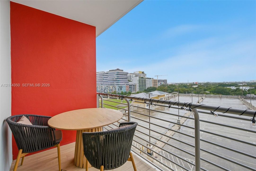 Private balcony featuring wood-finish flooring, metal railing, and a vibrant red accent wall